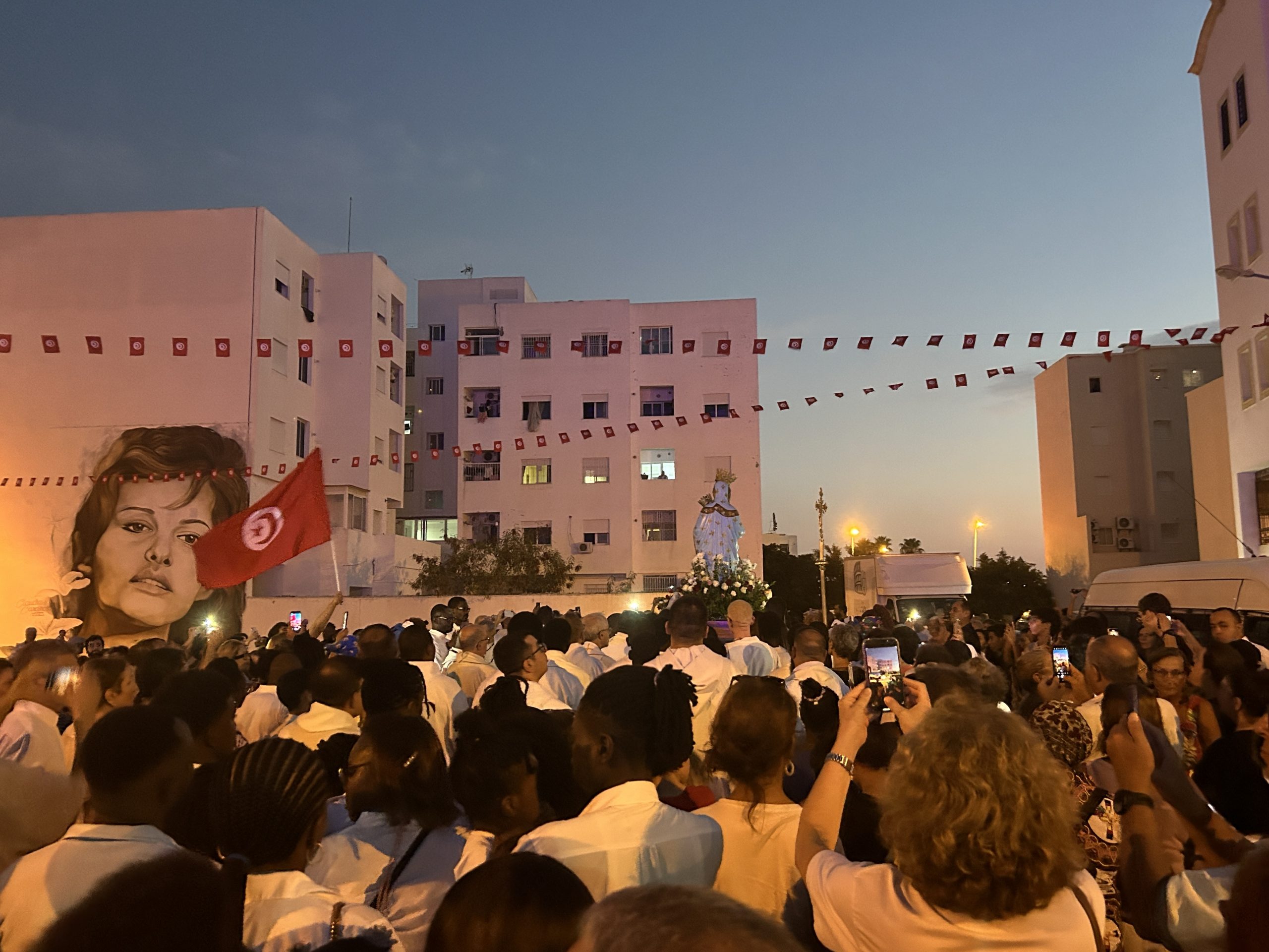 A statue of the Virgin Mary and a Tunisian flag in front of the mural of Claudia Cardinale in La Goulette, Tunisia